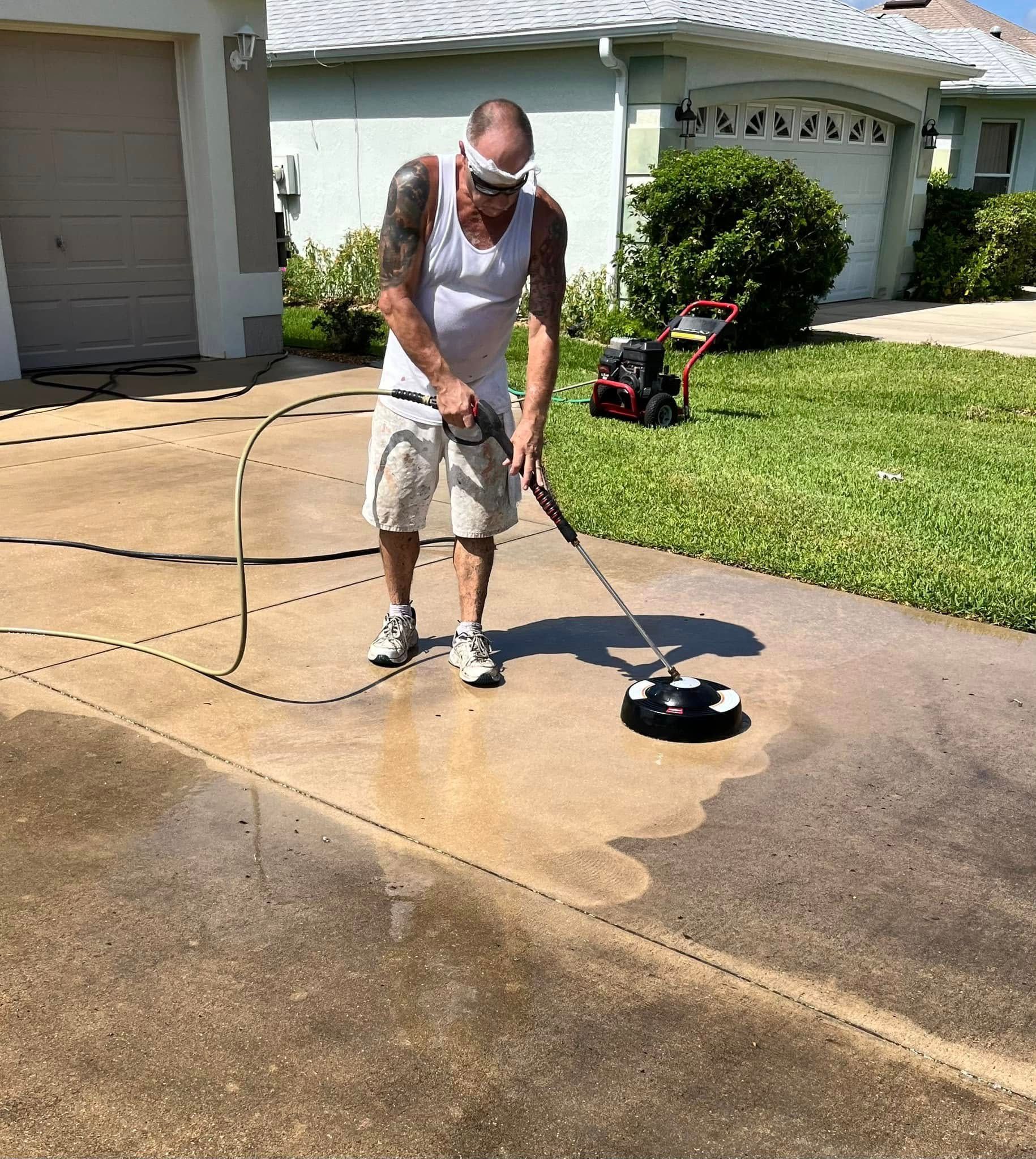 A man is cleaning a driveway with a pressure washer.