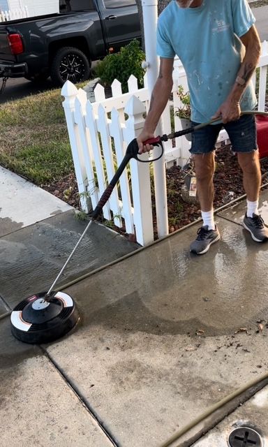 A man is cleaning a driveway with a pressure washer.