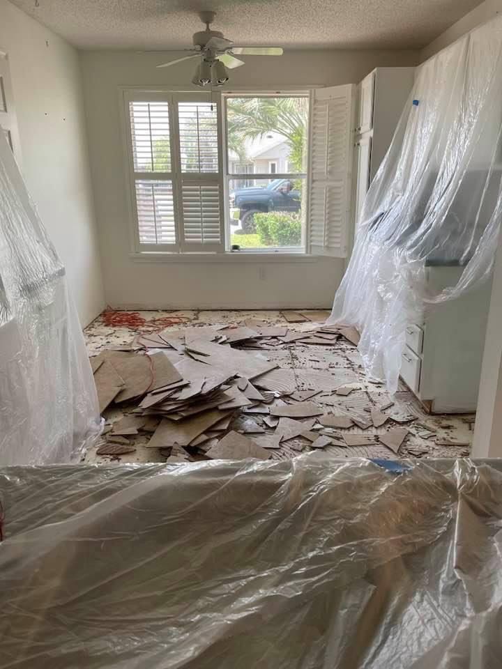 A room with a lot of trash on the floor and a ceiling fan.