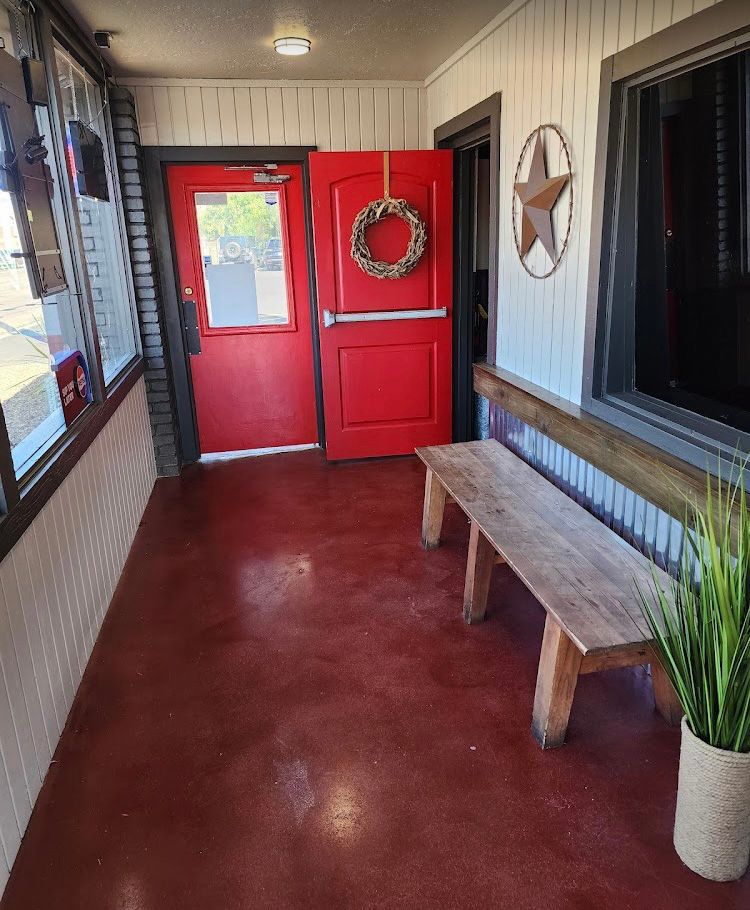 An entryway with red doors and flooring, a wooden bench, and a rustic star.