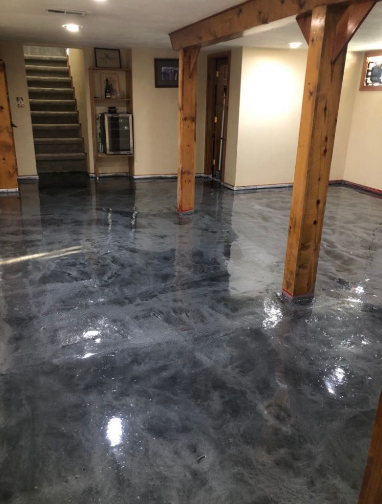Metallic epoxy flooring in a basement with wood support beams and stairs.