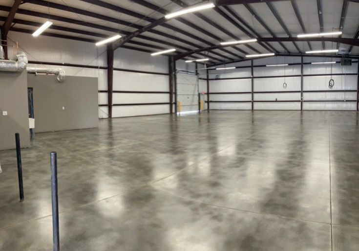 Empty warehouse with a polished concrete floor and metal framing.
