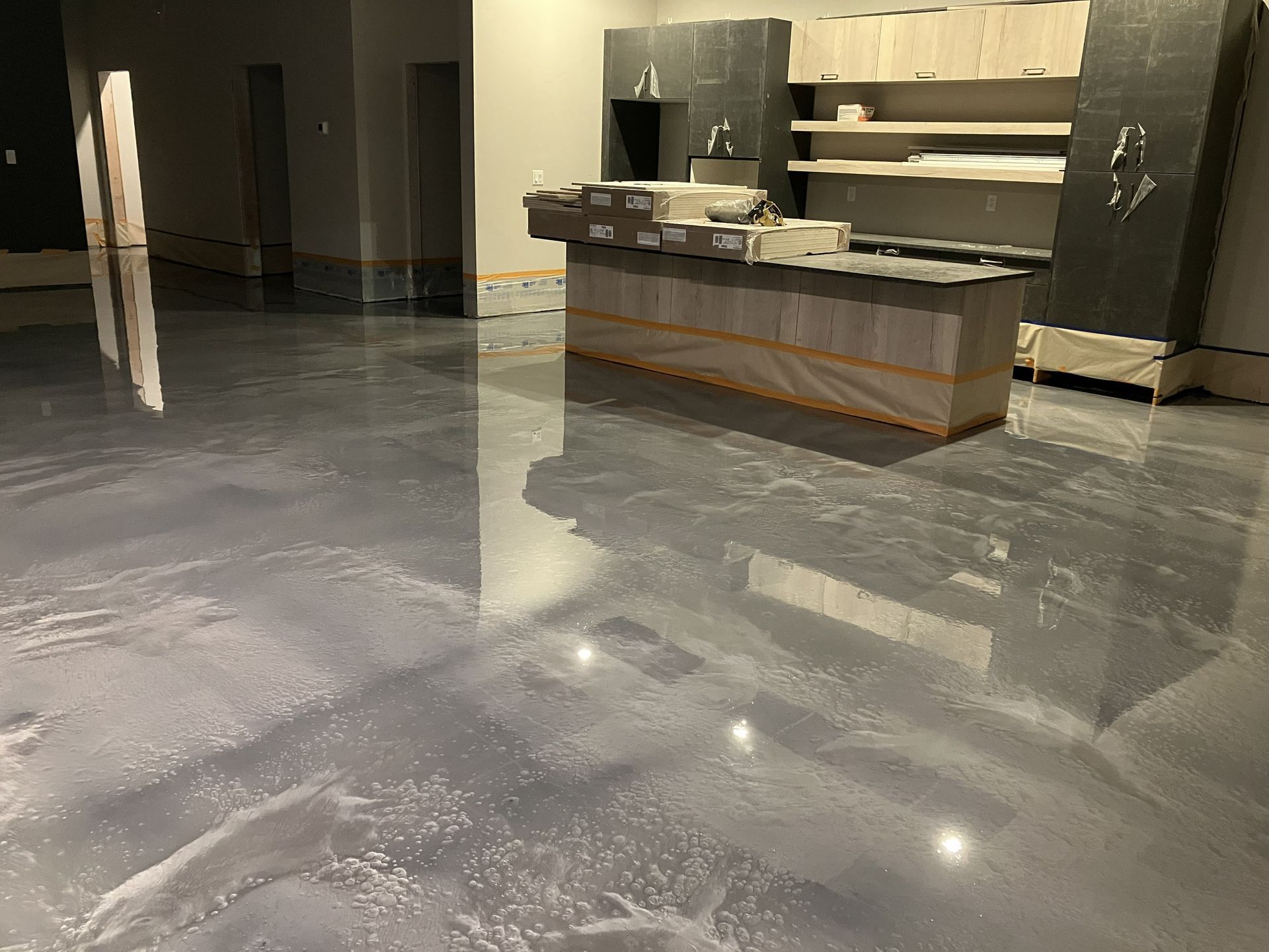 Gray epoxy floor with a reflective sheen. Kitchen island under construction.
