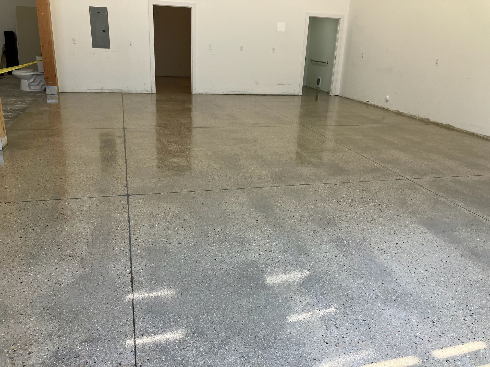 Polished gray concrete floor in a bright room, with doors and walls in the background.