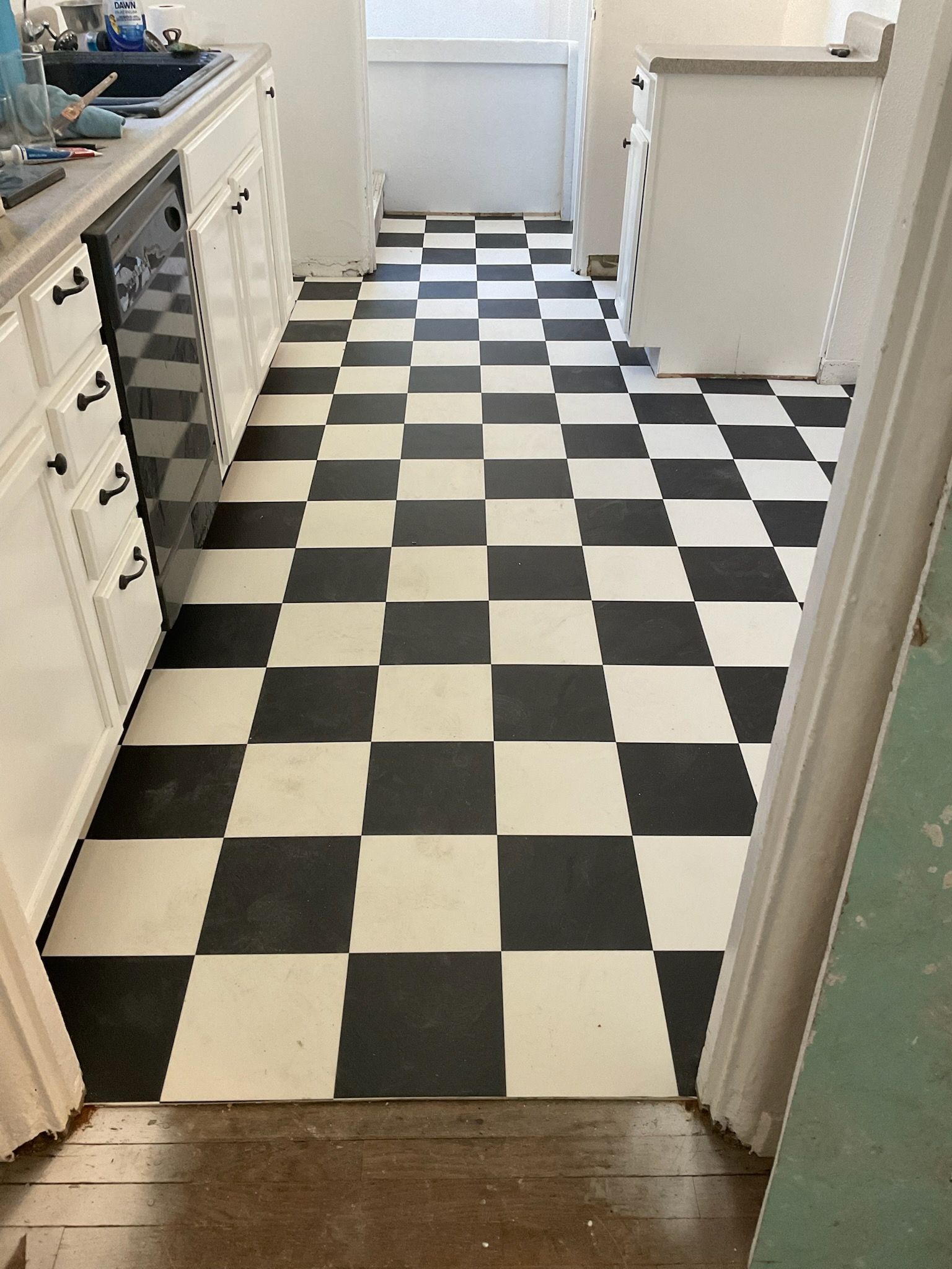 Black and white checkered kitchen floor with white cabinets and a dishwasher.