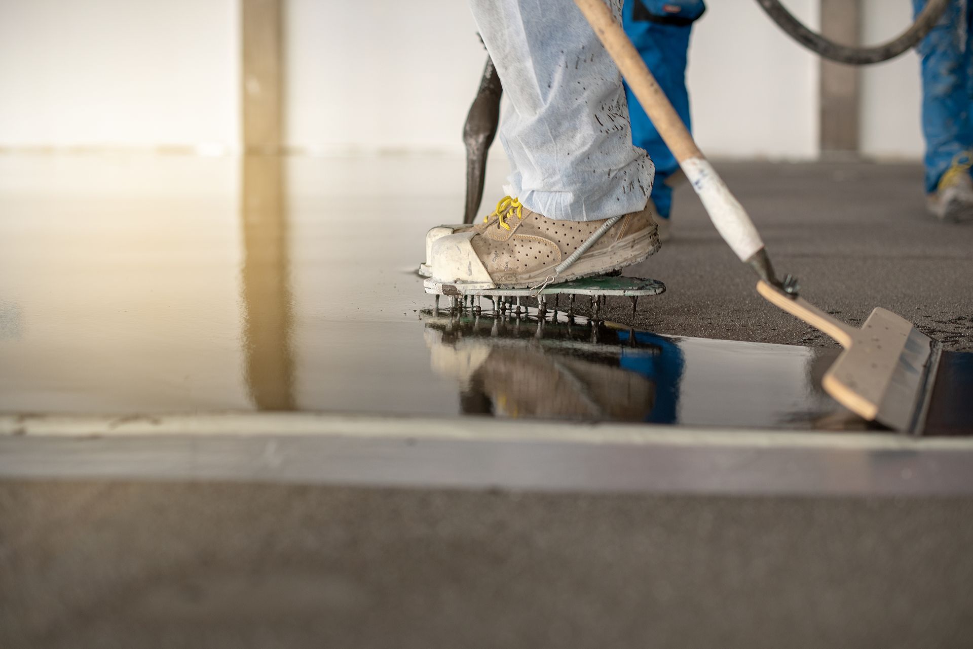 Person applying epoxy floor coating with spiked shoes and a spreader.