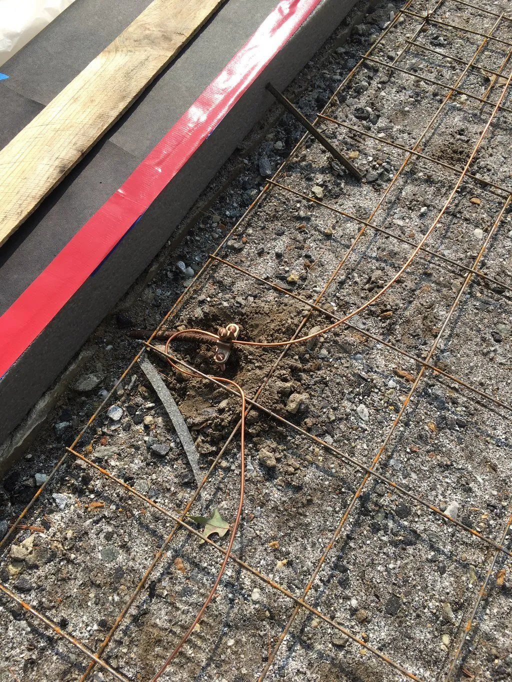 Concrete reinforcement mesh with dirt and a red and black level.