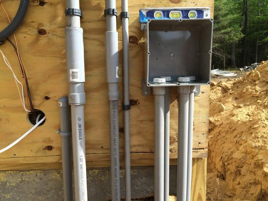 Electrical conduit and junction box mounted on plywood. A level sits on top.