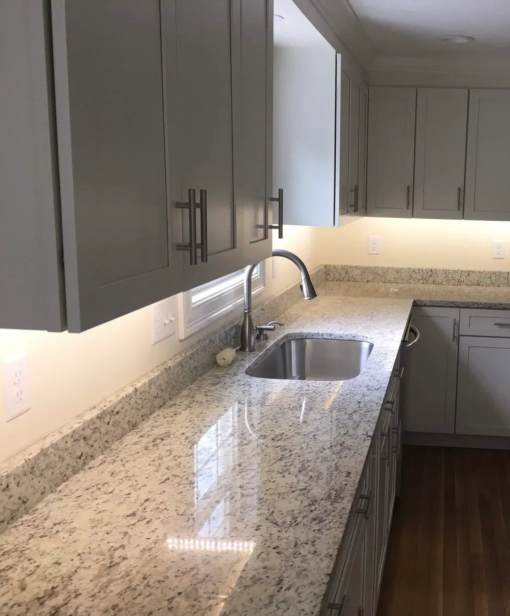 Kitchen with gray cabinets, granite countertops, and a stainless steel sink.