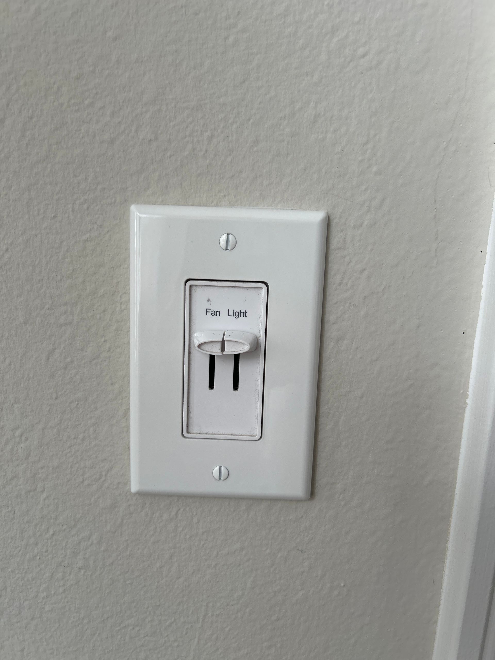 White light switch with on/off slider, mounted on a white wall.