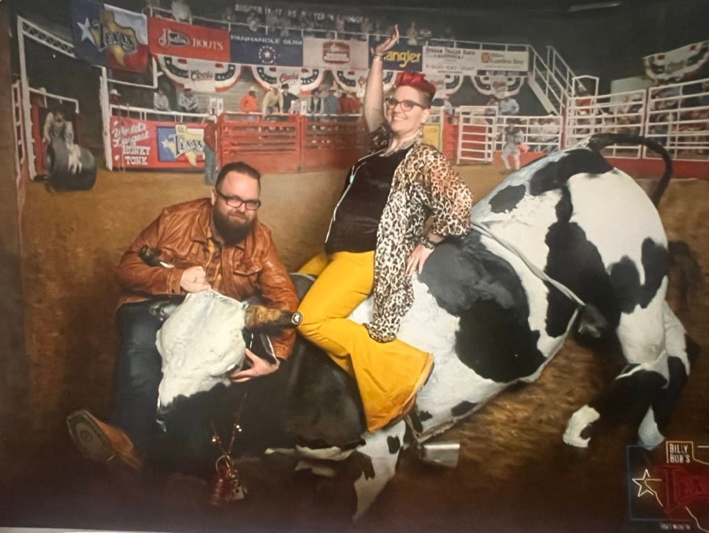 A man and a woman are riding a bull in a rodeo arena.