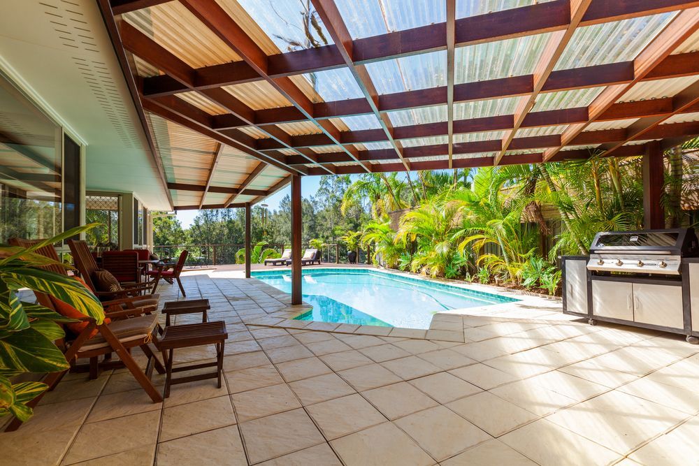 A Covered Patio With a Swimming Pool and a Grill — Paul Cooper Homes In Noosa Heads, QLD