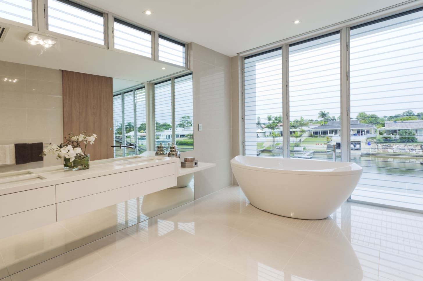 A Bathroom With a Bathtub, Sink, Mirror and Large Windows — Paul Cooper Homes In Noosa Heads, QLD