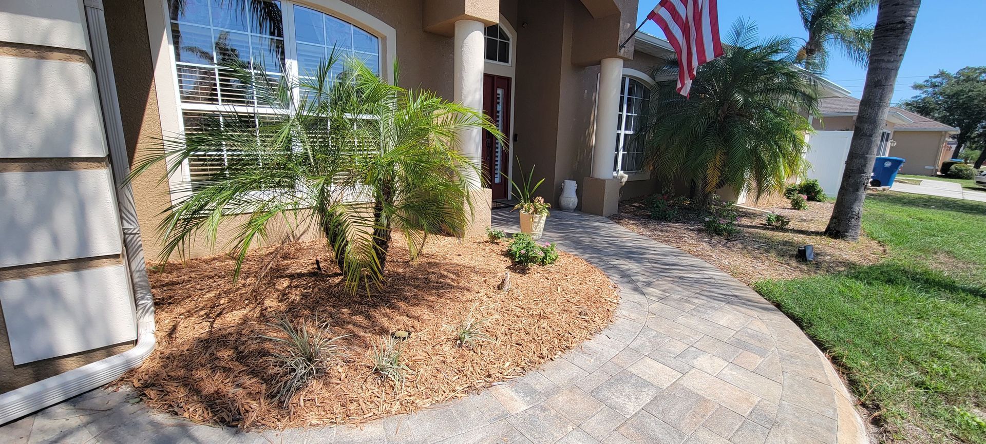 A walkway leading to a house with a flag in the background.