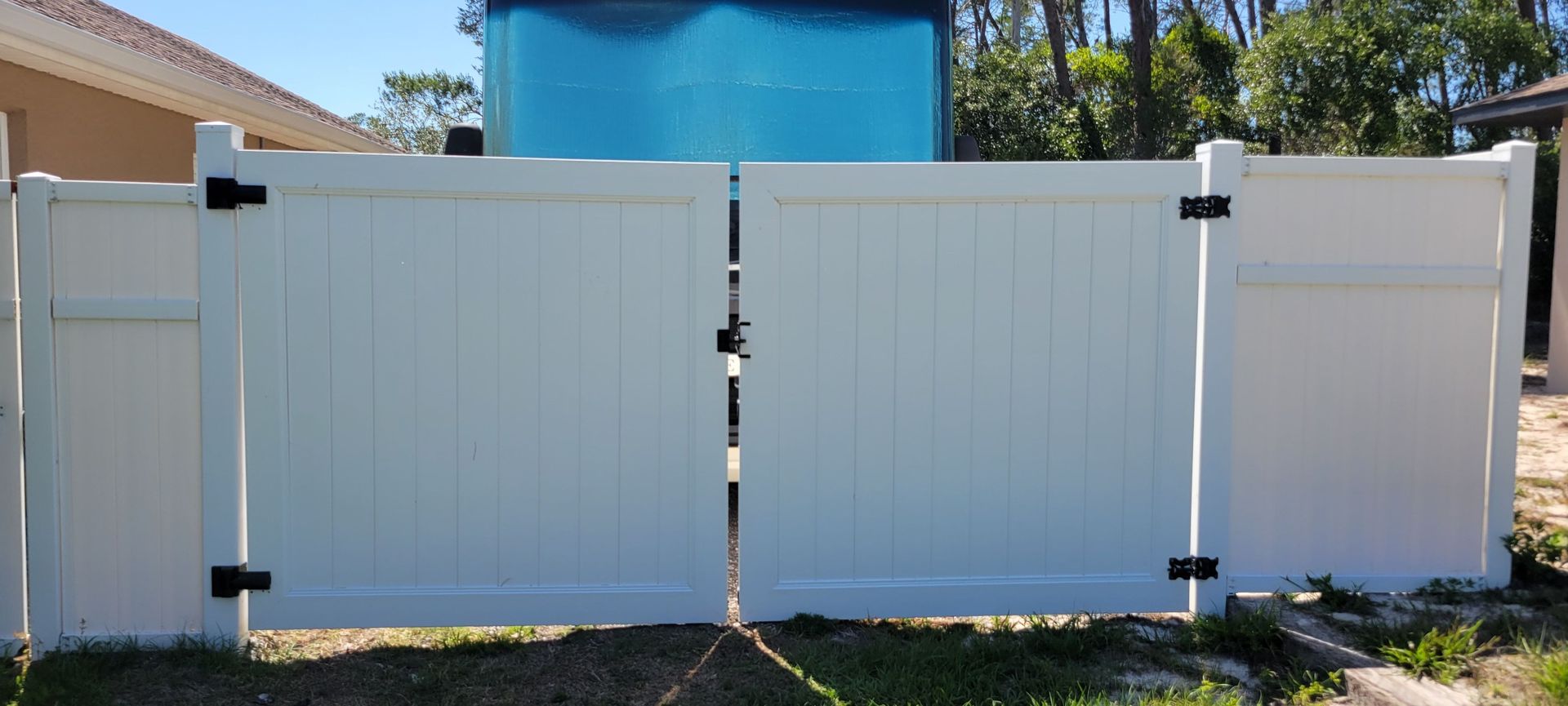 A white fence with a blue tank in the background.