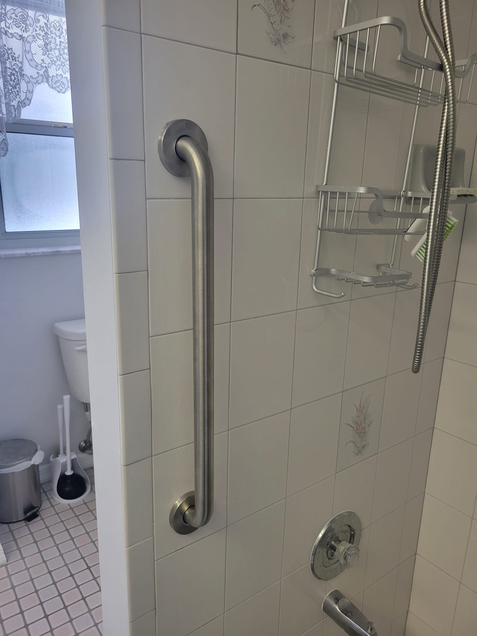 A bathroom with a stainless steel handle on the wall.