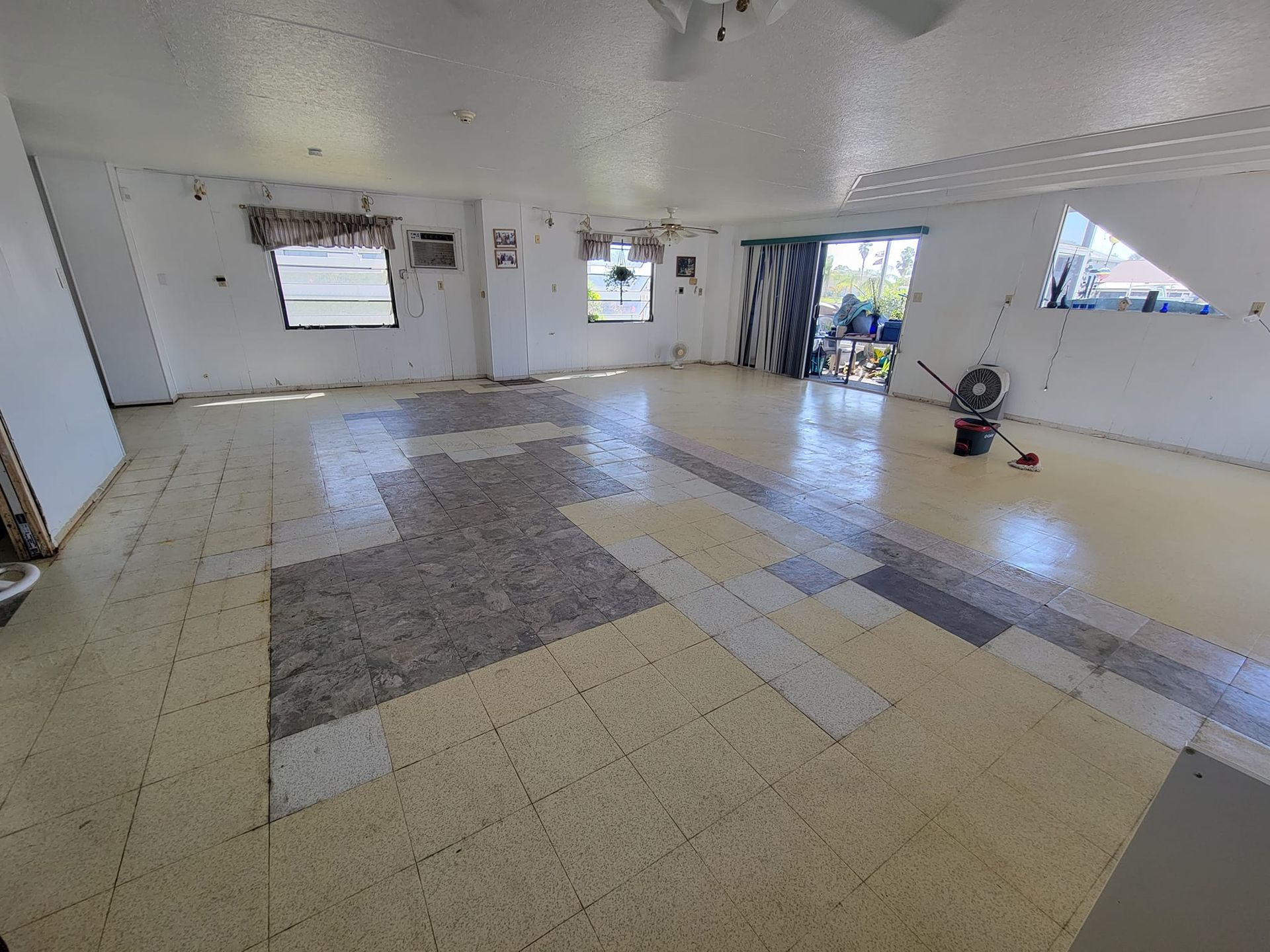 A large room with a tiled floor and a fan on the floor.