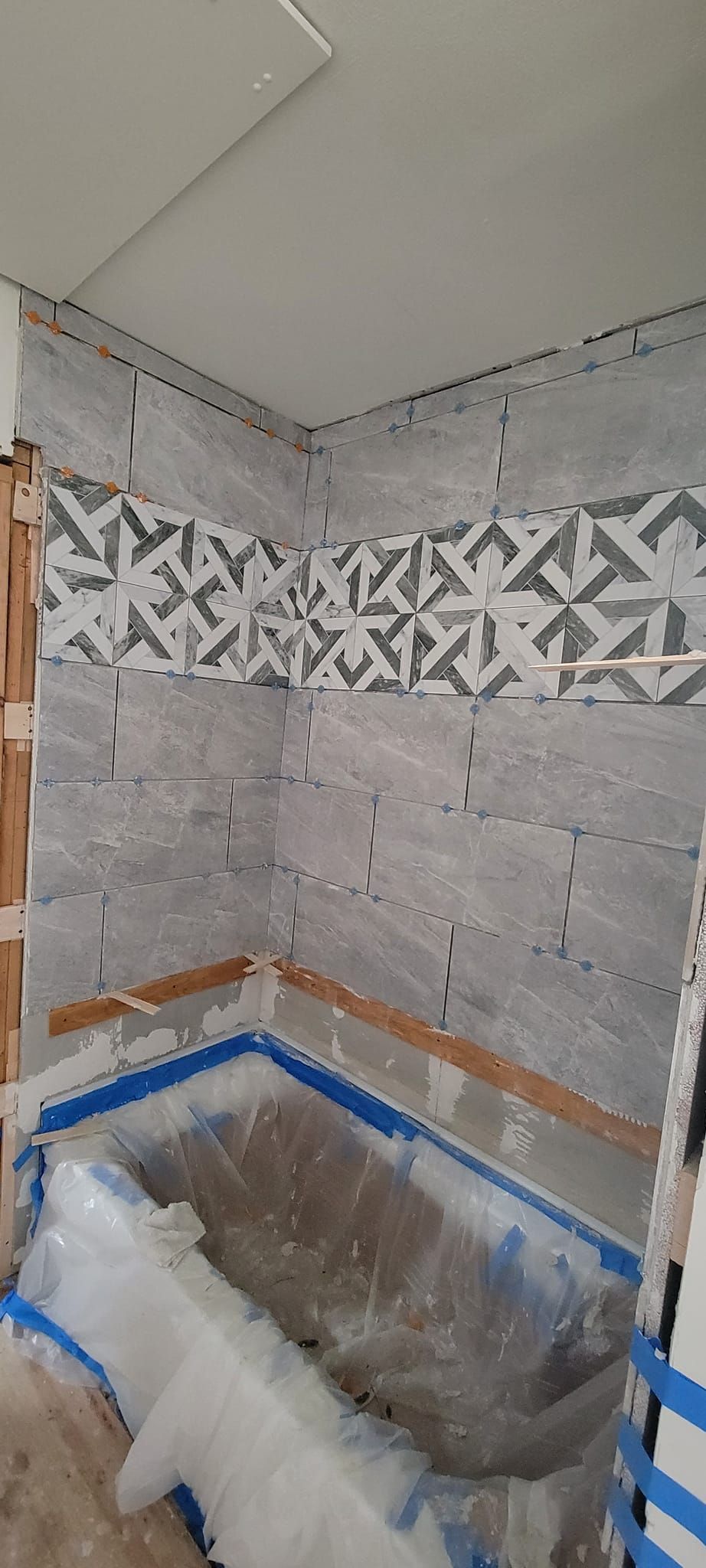 A bathroom under construction with a bathtub covered in plastic.