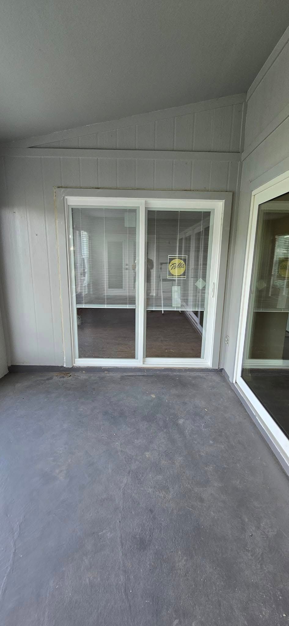 An empty room with a sliding glass door and blinds.