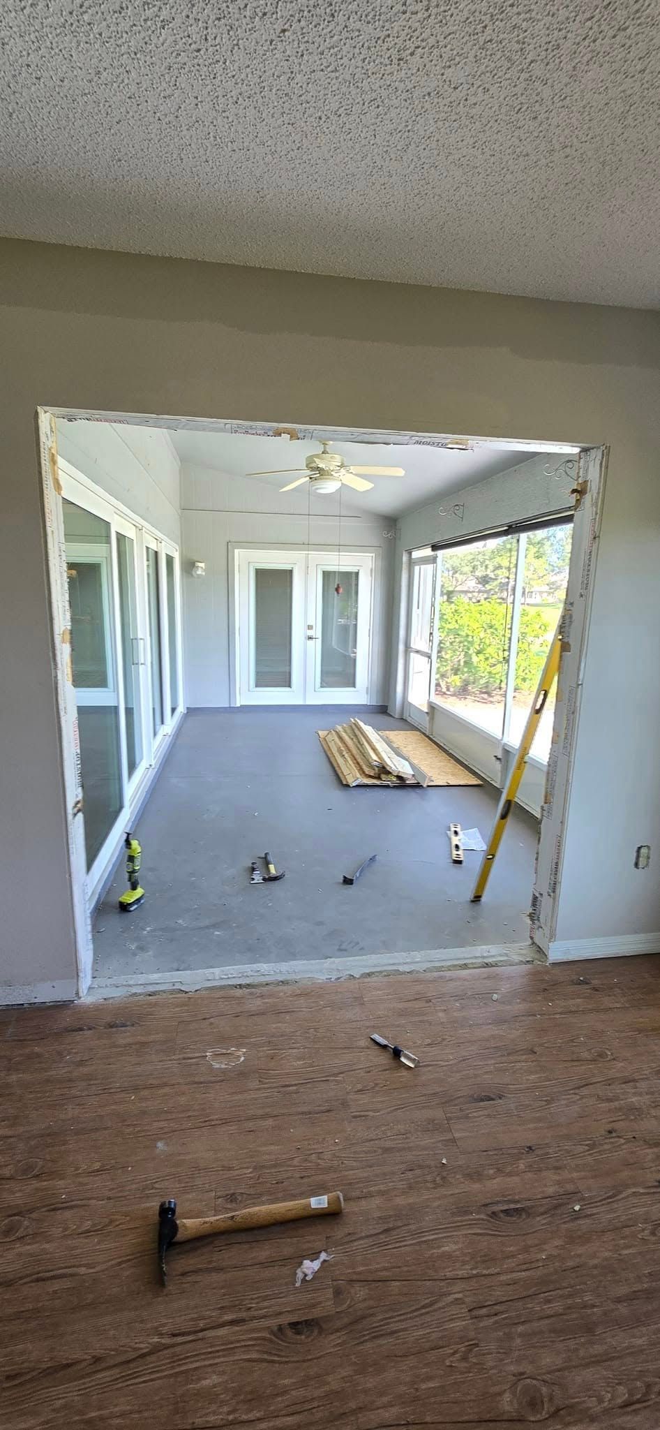 A room with a hole in the wall and a hammer on the floor.