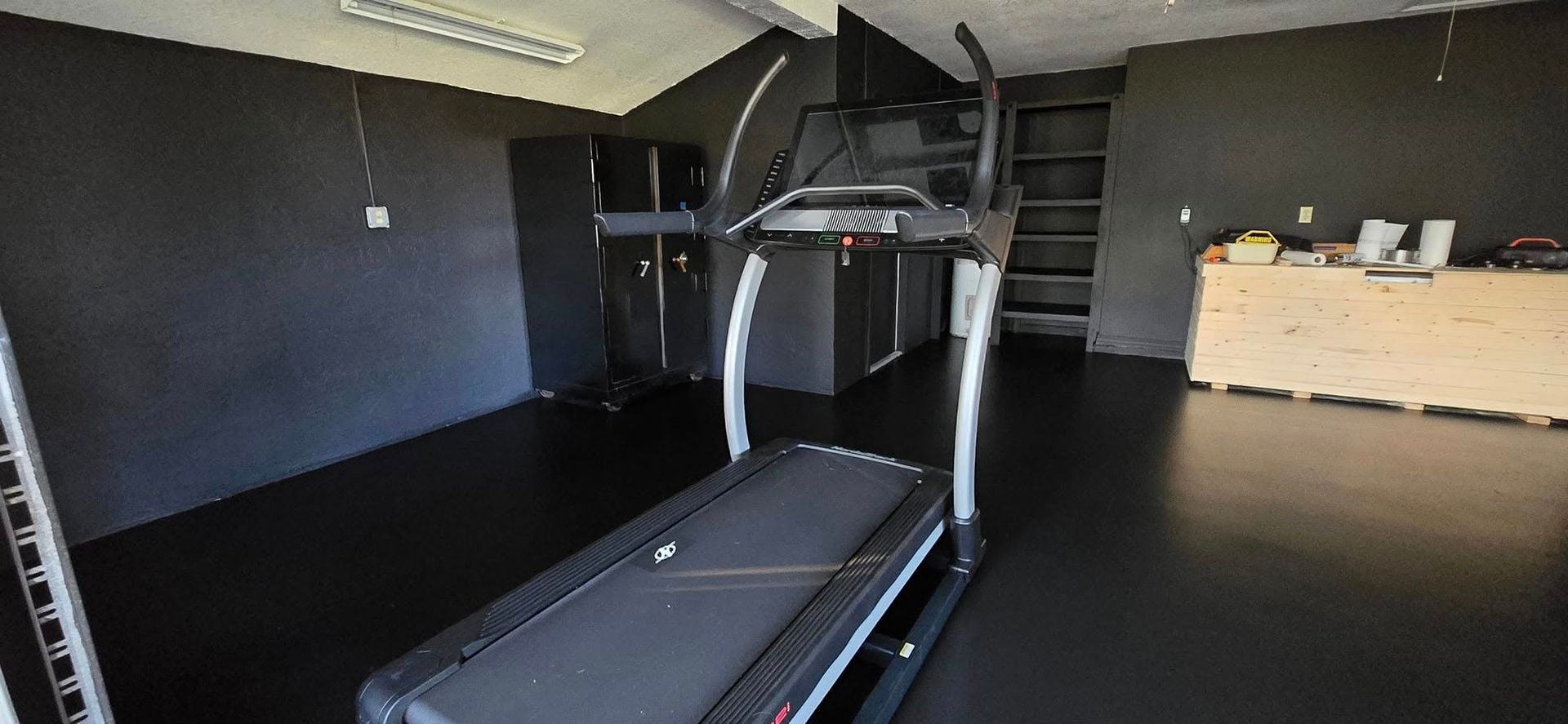 A treadmill is sitting on a black floor in a room.