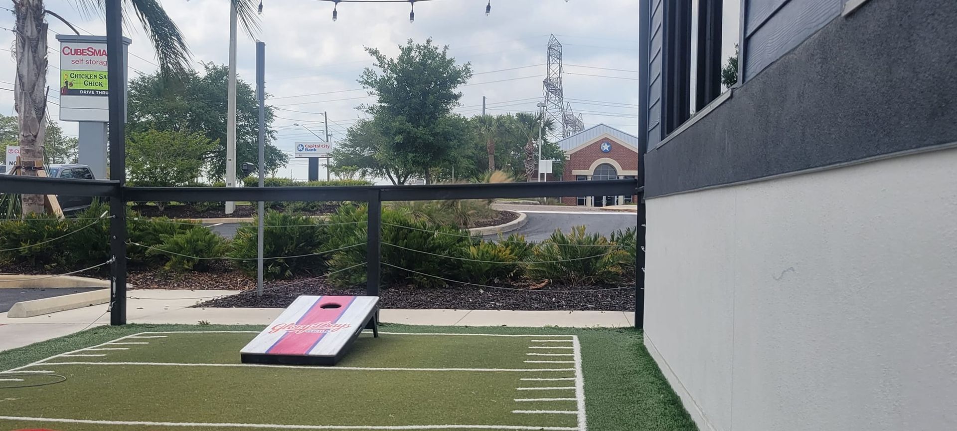 A cornhole game is being played in front of a building.