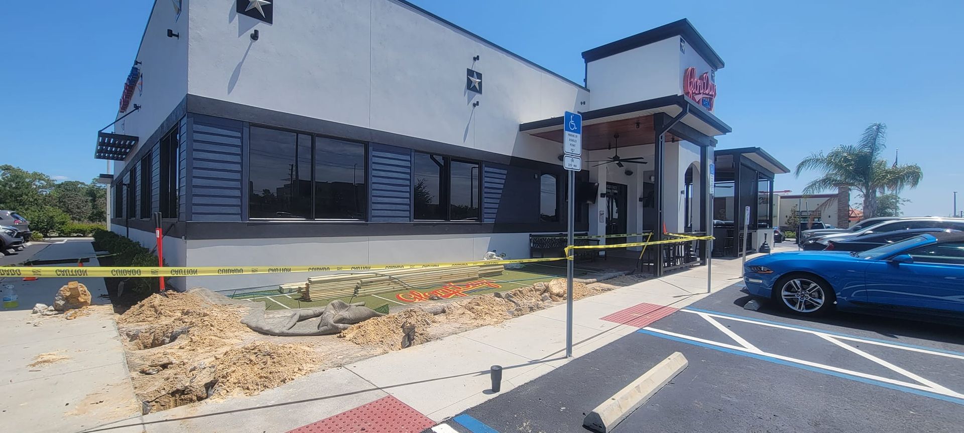 A blue car is parked in front of a building that is being remodeled.