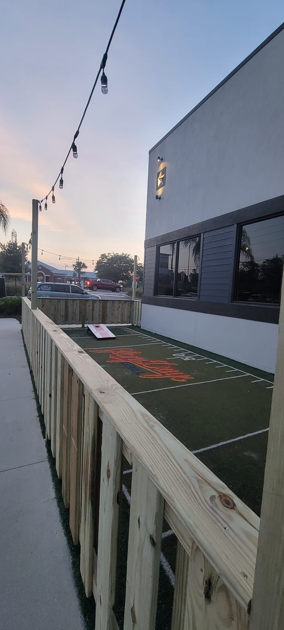A wooden fence surrounds a soccer field in front of a building.