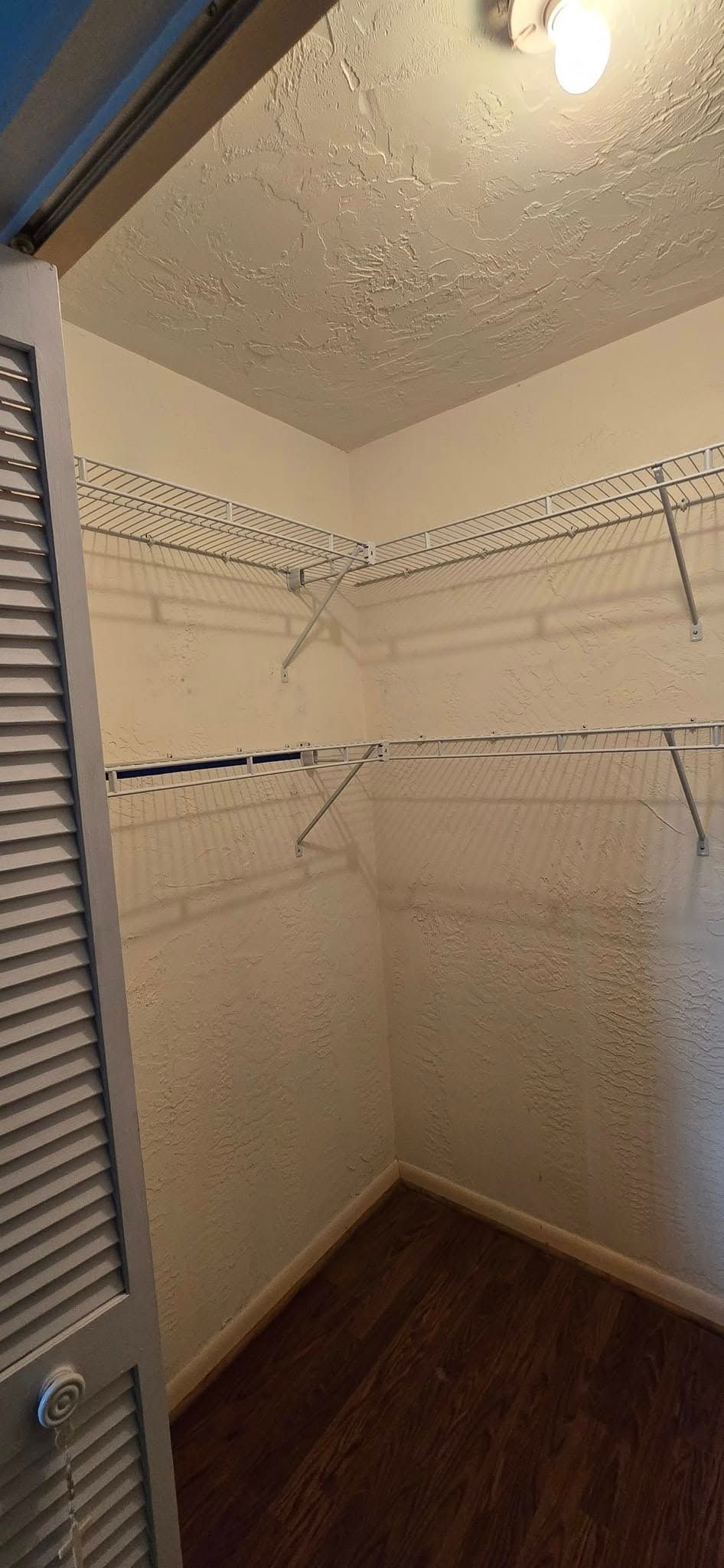 A closet with a lot of shelves and a light on the ceiling.