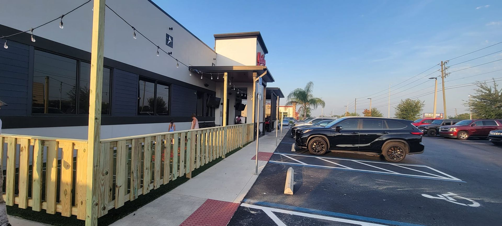 A car is parked in front of a building with a wooden fence.