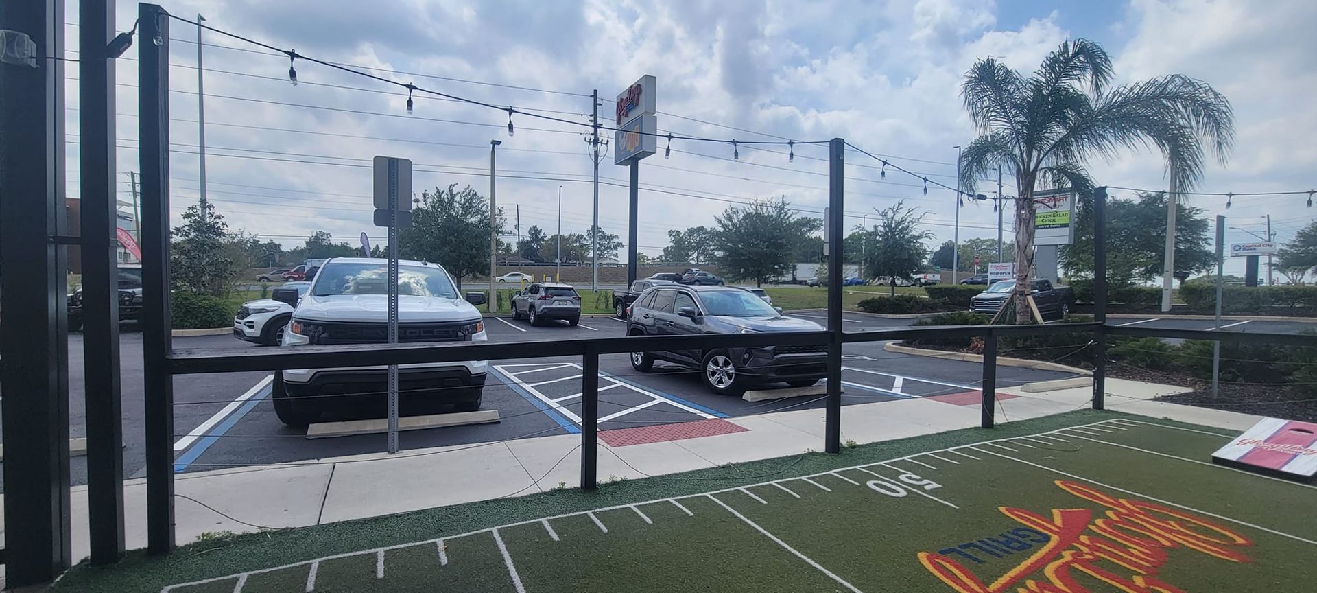 A lot of cars are parked in a parking lot behind a fence.