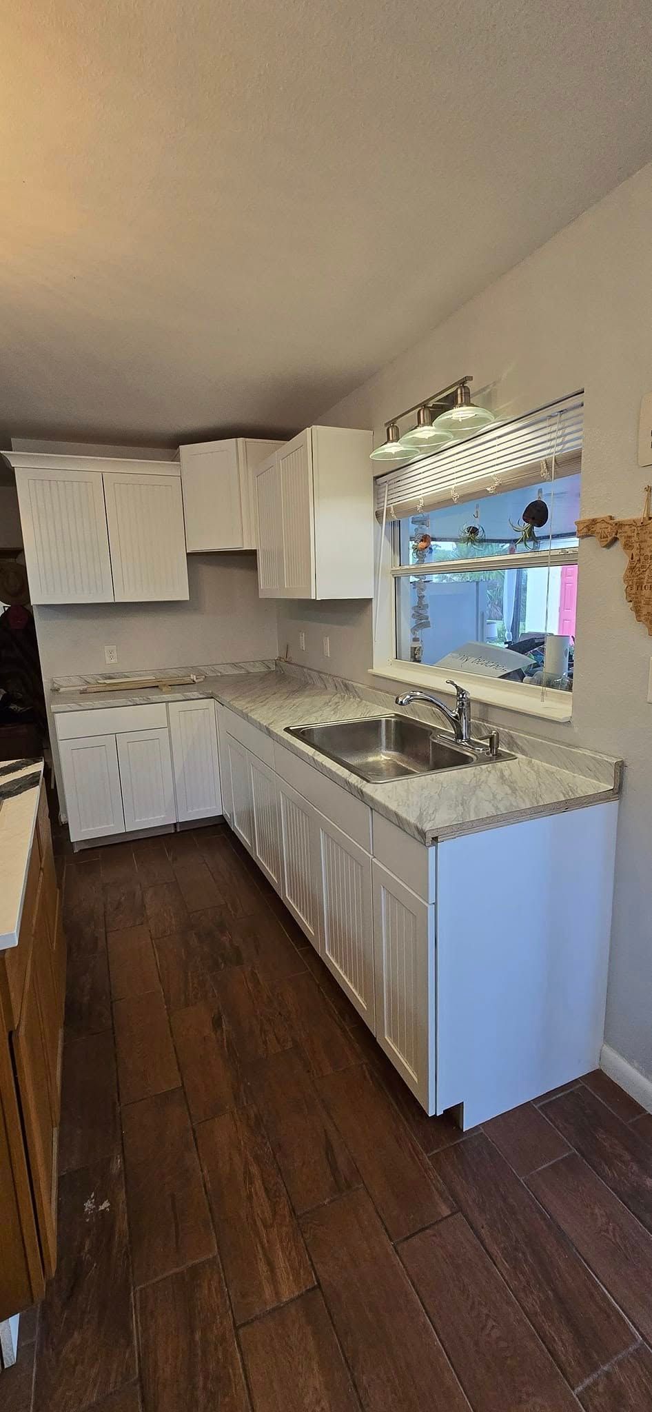 A kitchen with white cabinets , granite counter tops , and a sink.