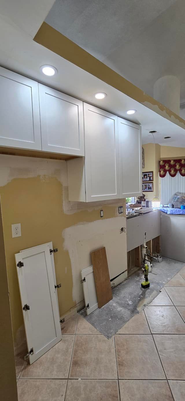 A kitchen is being remodeled with white cabinets and tile floors.