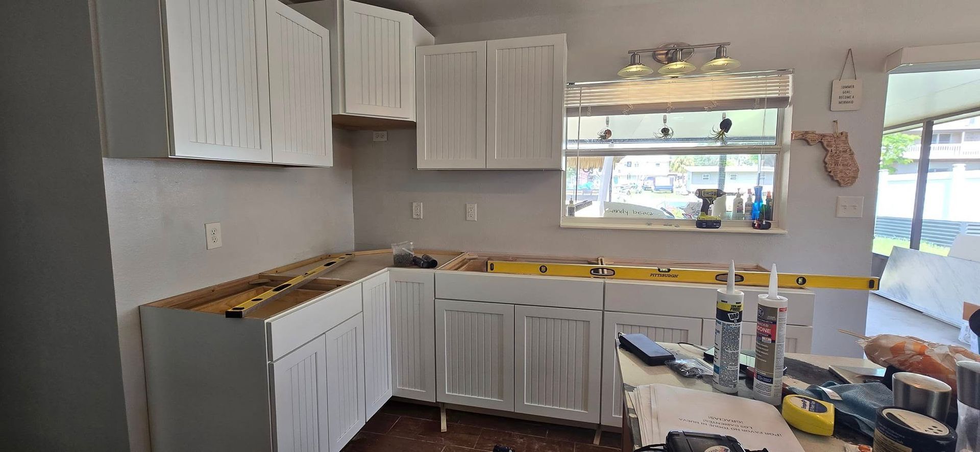 A kitchen is being remodeled with white cabinets and a window.
