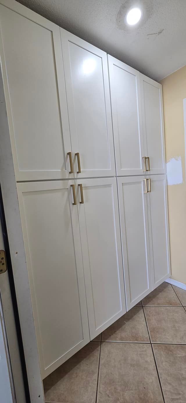 A room with a lot of white cabinets and a tile floor.