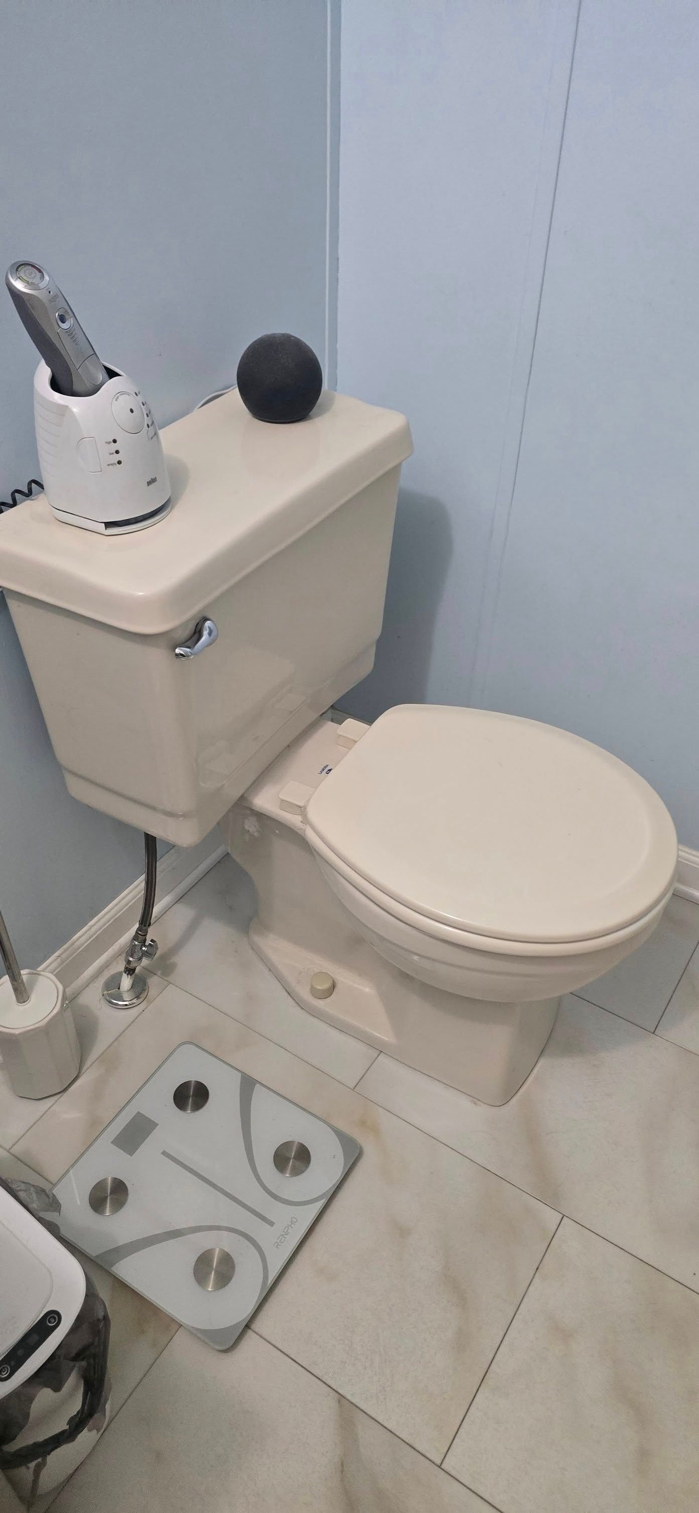A toilet is sitting in a bathroom next to a scale.
