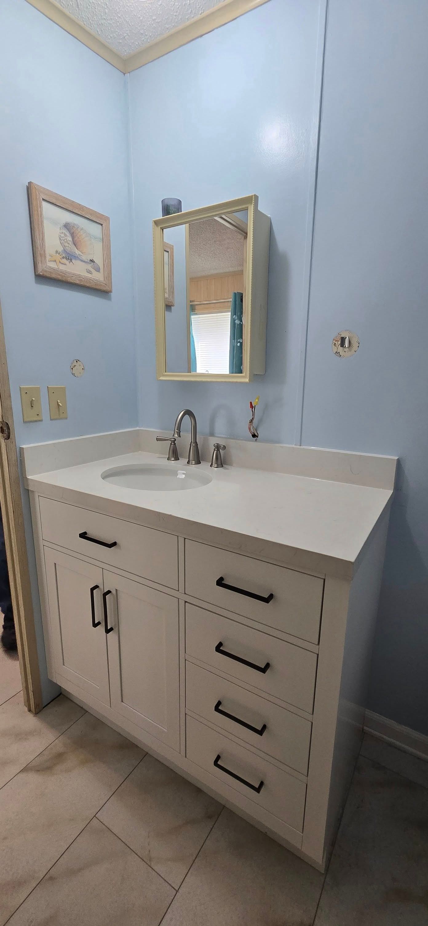 A bathroom with a sink , mirror and medicine cabinet.