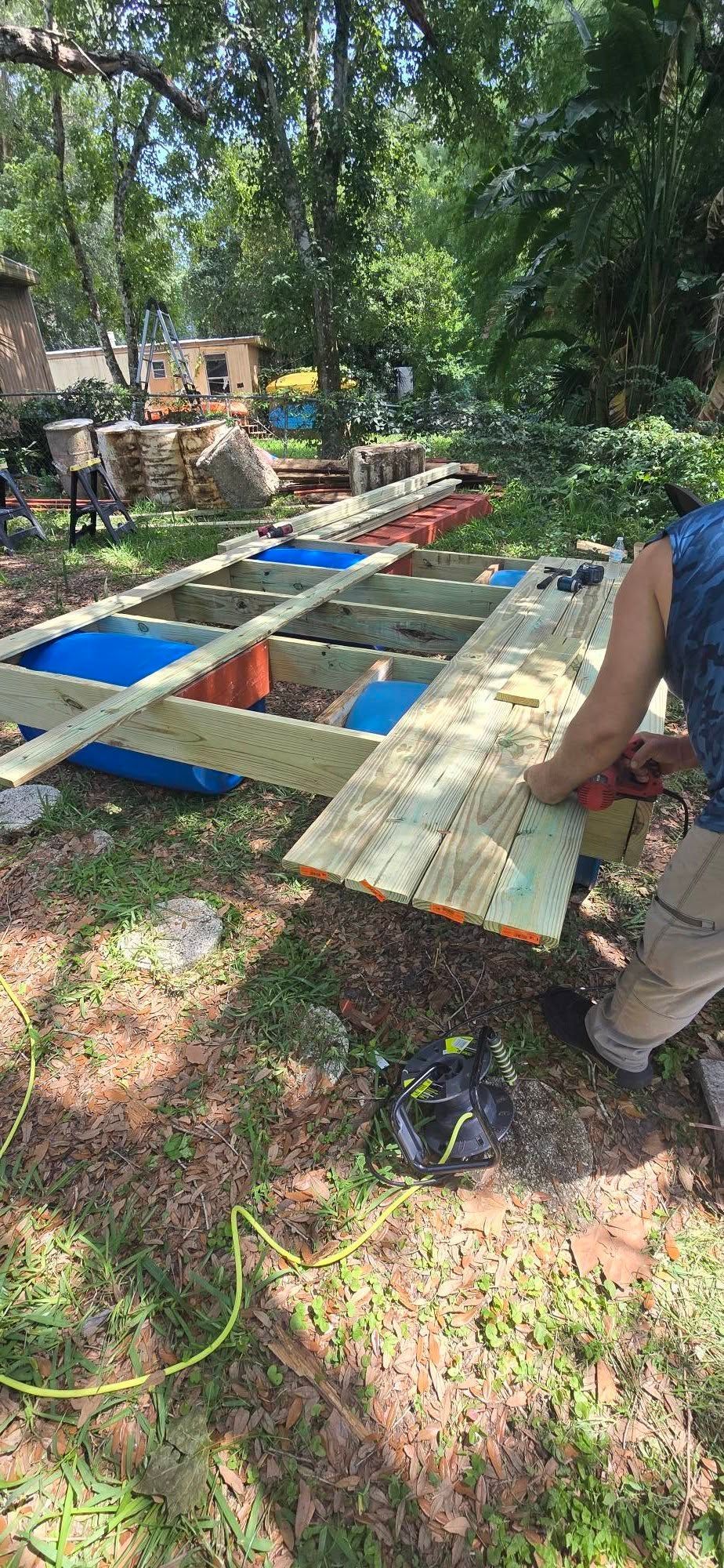 A man is cutting a piece of wood in the grass.