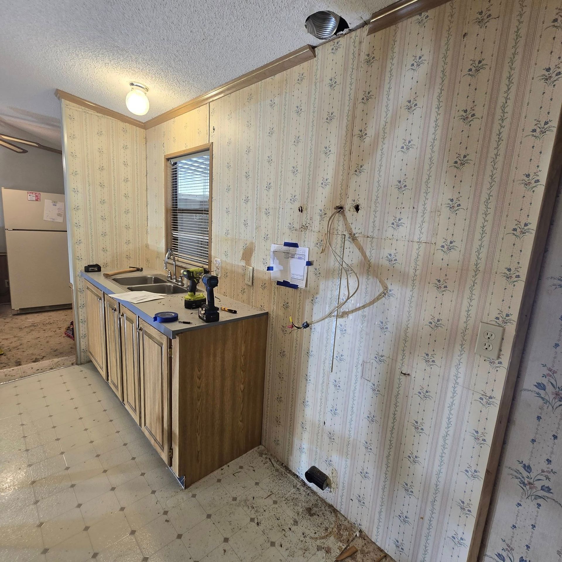 A kitchen with a sink and a drill on the counter