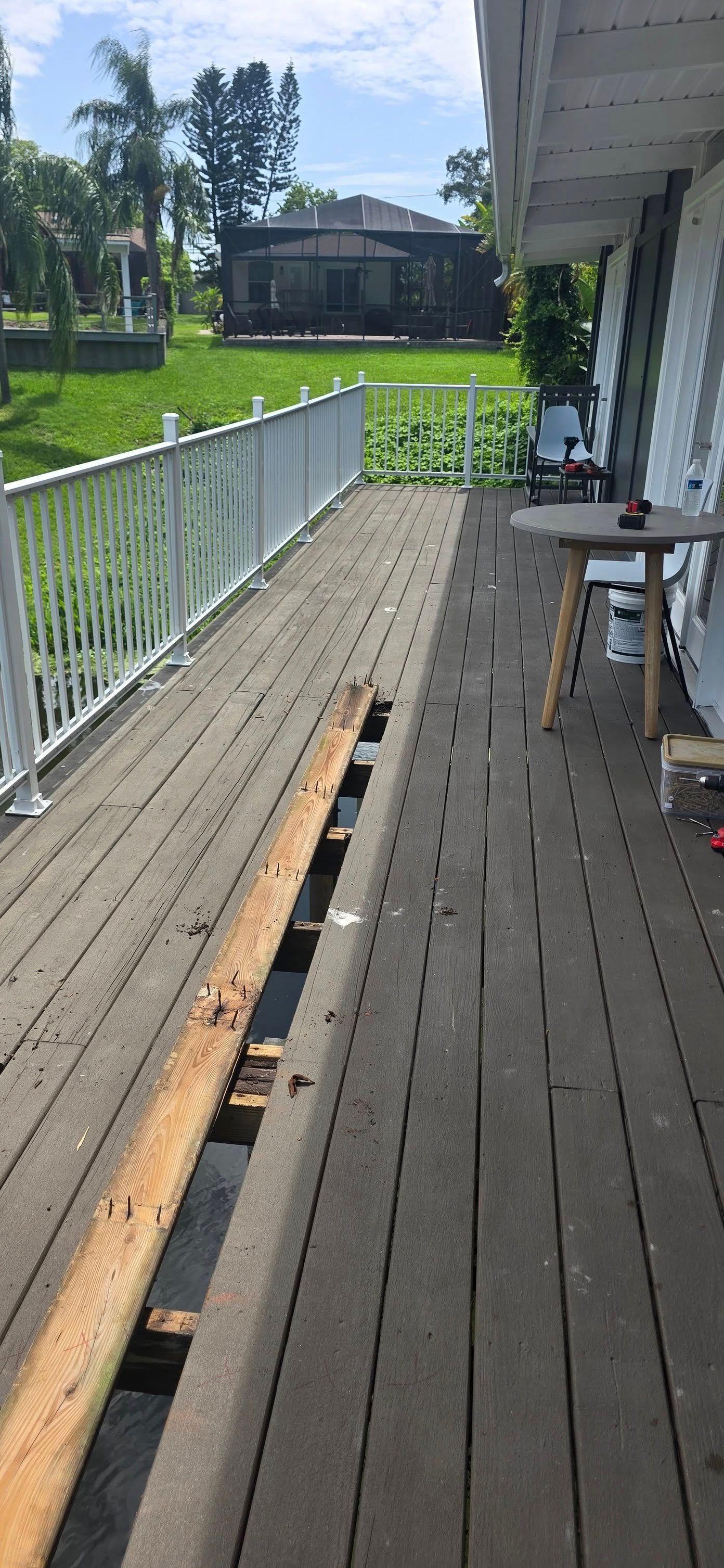 A wooden deck with a white railing and a table on it.