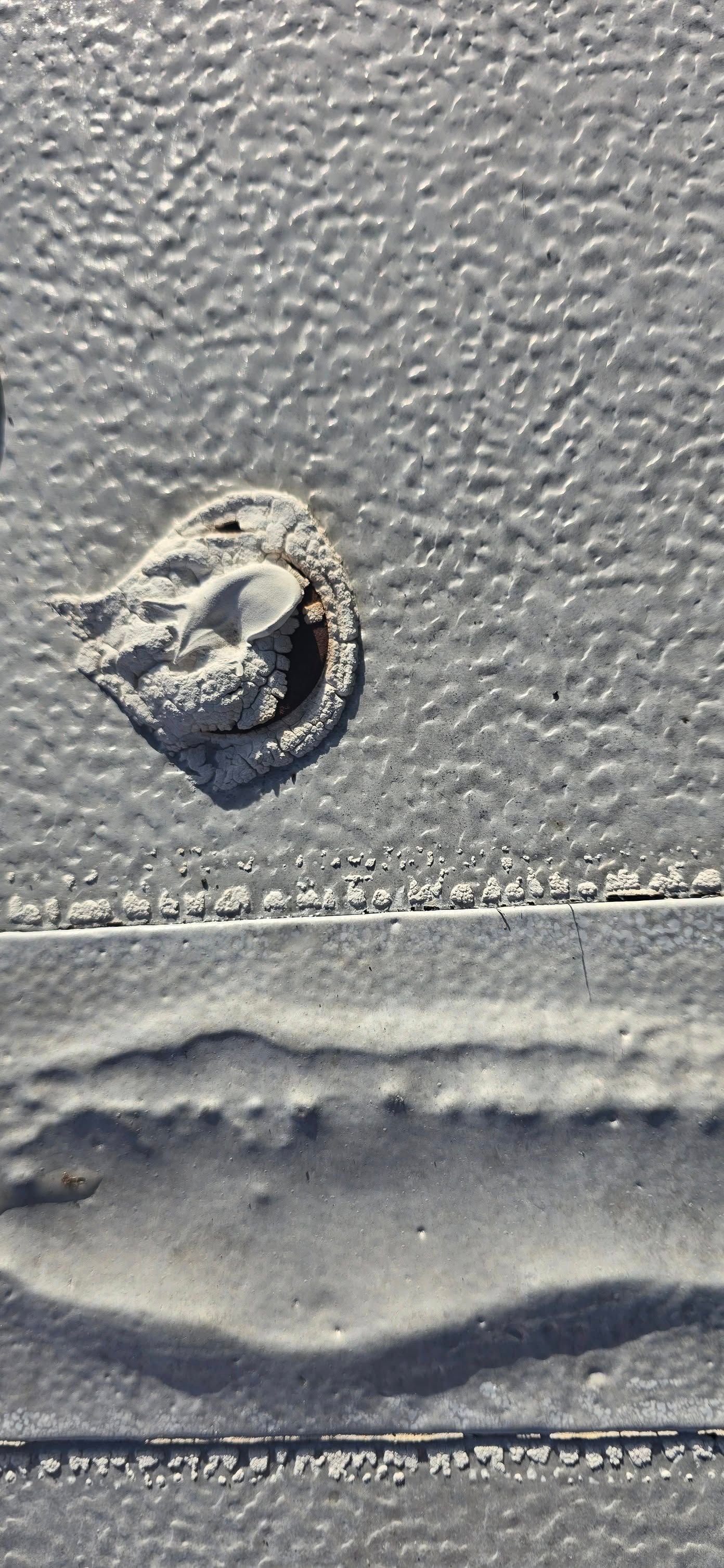 A black and white photo of a rock in the sand on a beach.