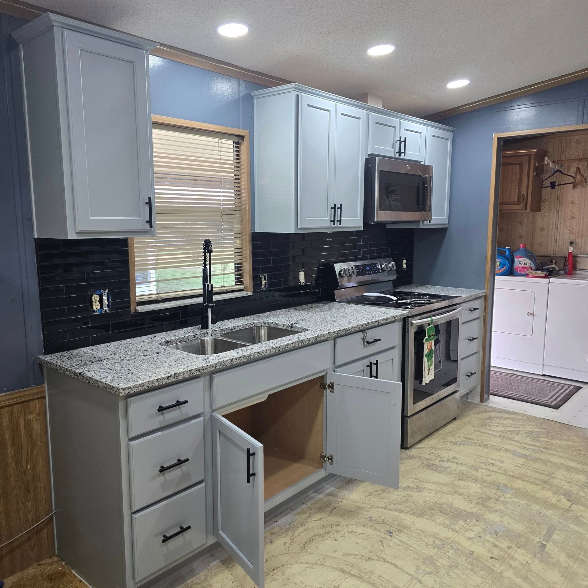 A kitchen with white cabinets , granite counter tops , stainless steel appliances and a sink.