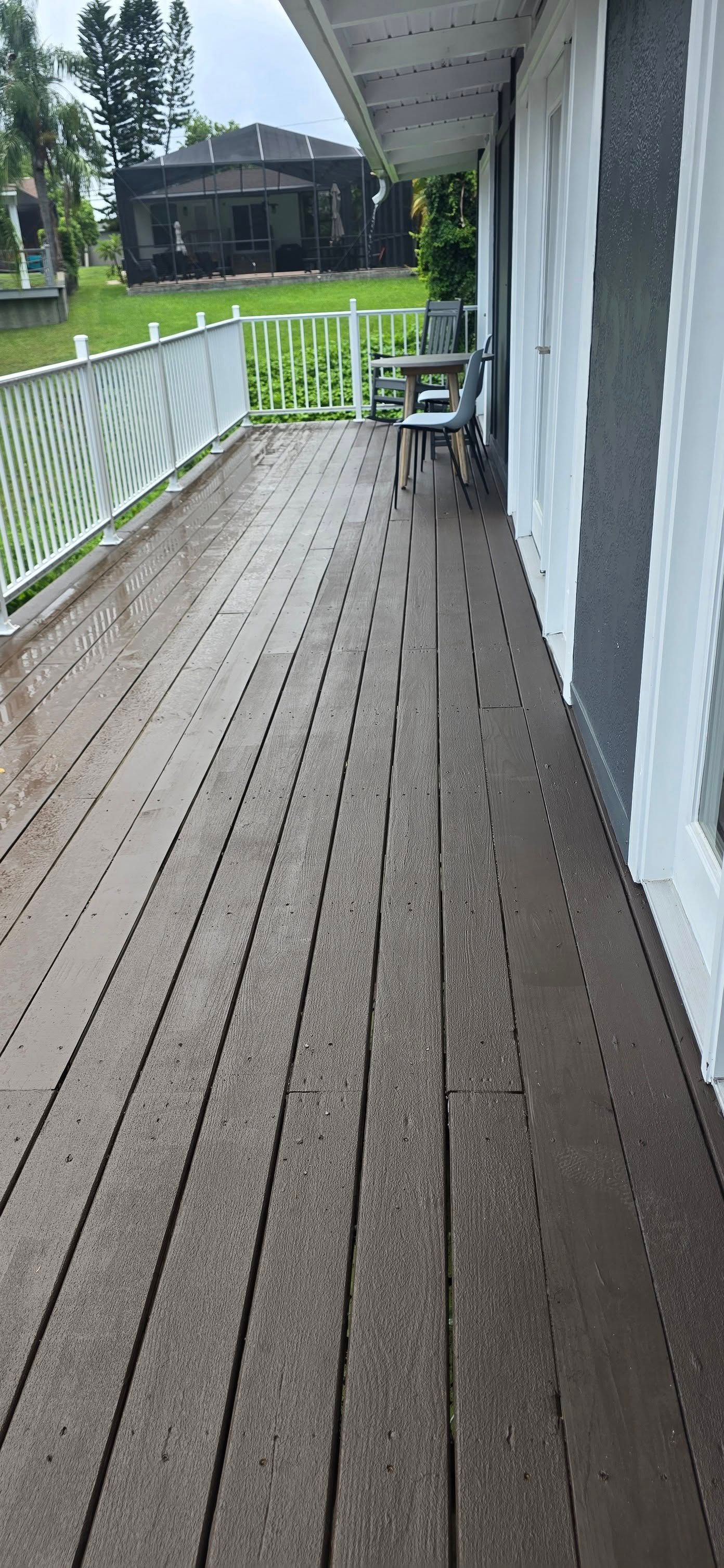 A long wooden deck with a table and chairs on it.