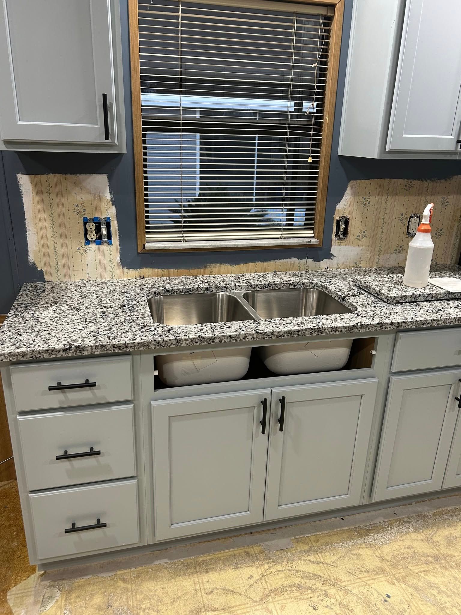 A kitchen with a sink , cabinets and a window.