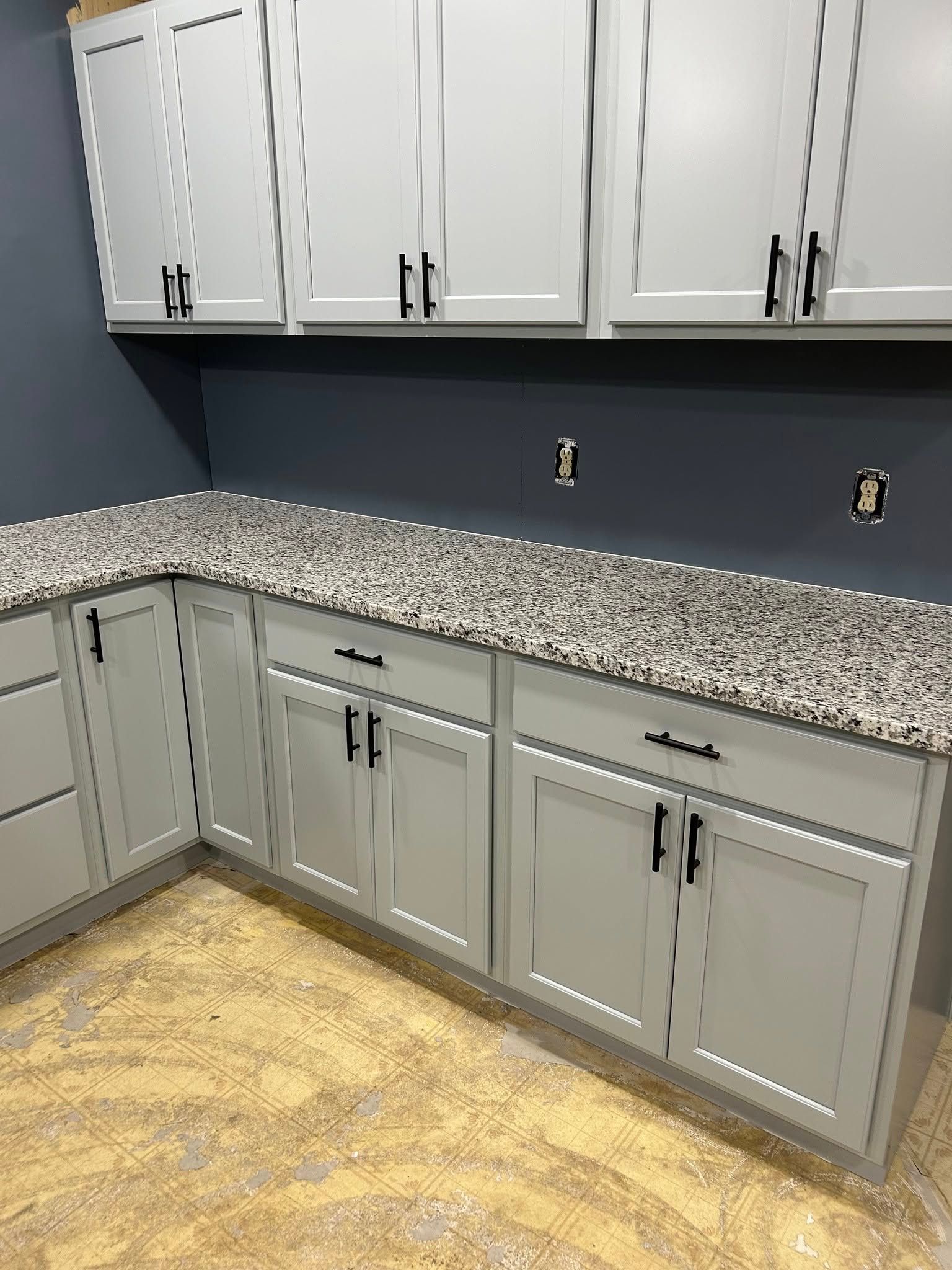 A kitchen with white cabinets and granite counter tops.