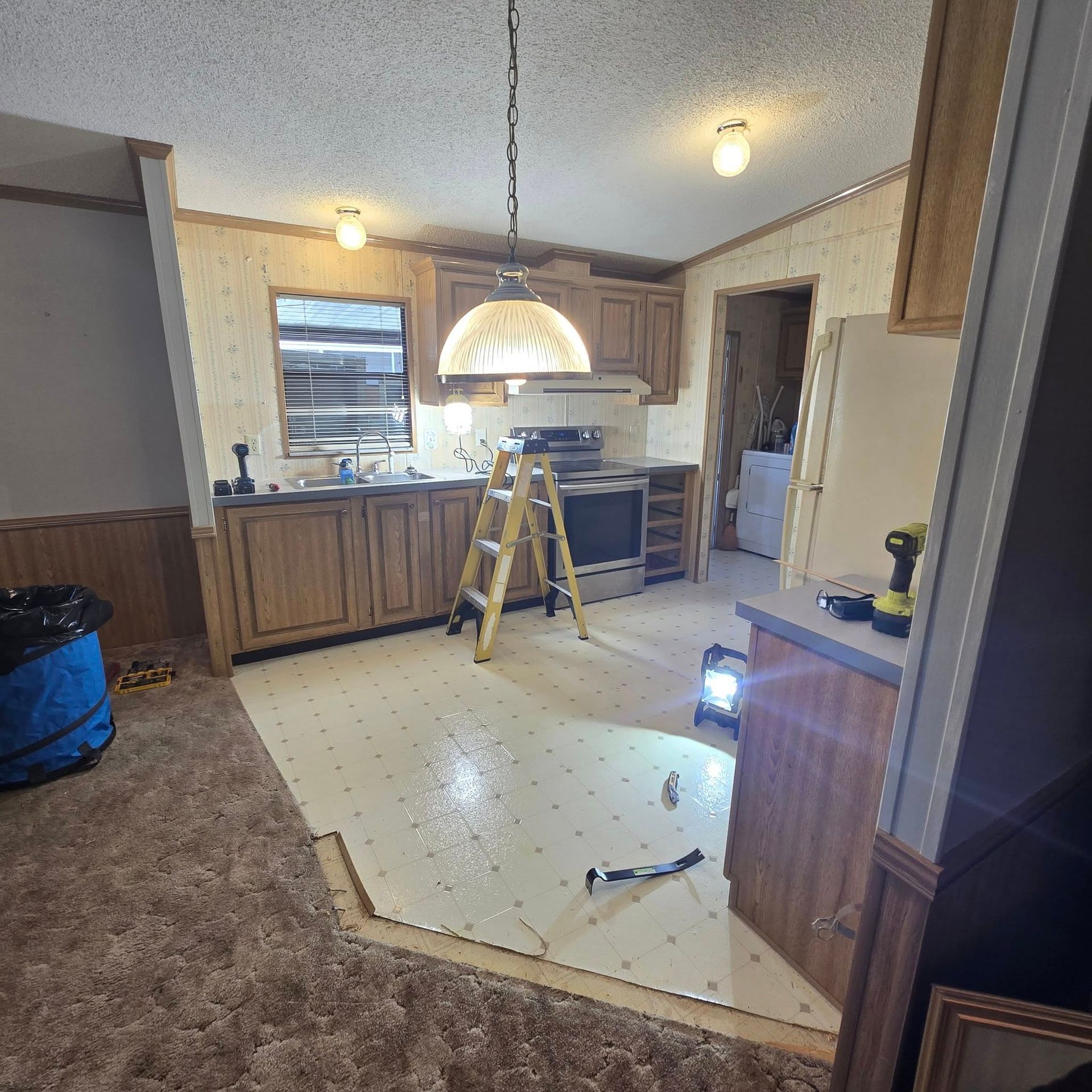 A kitchen with a ladder in the middle of it