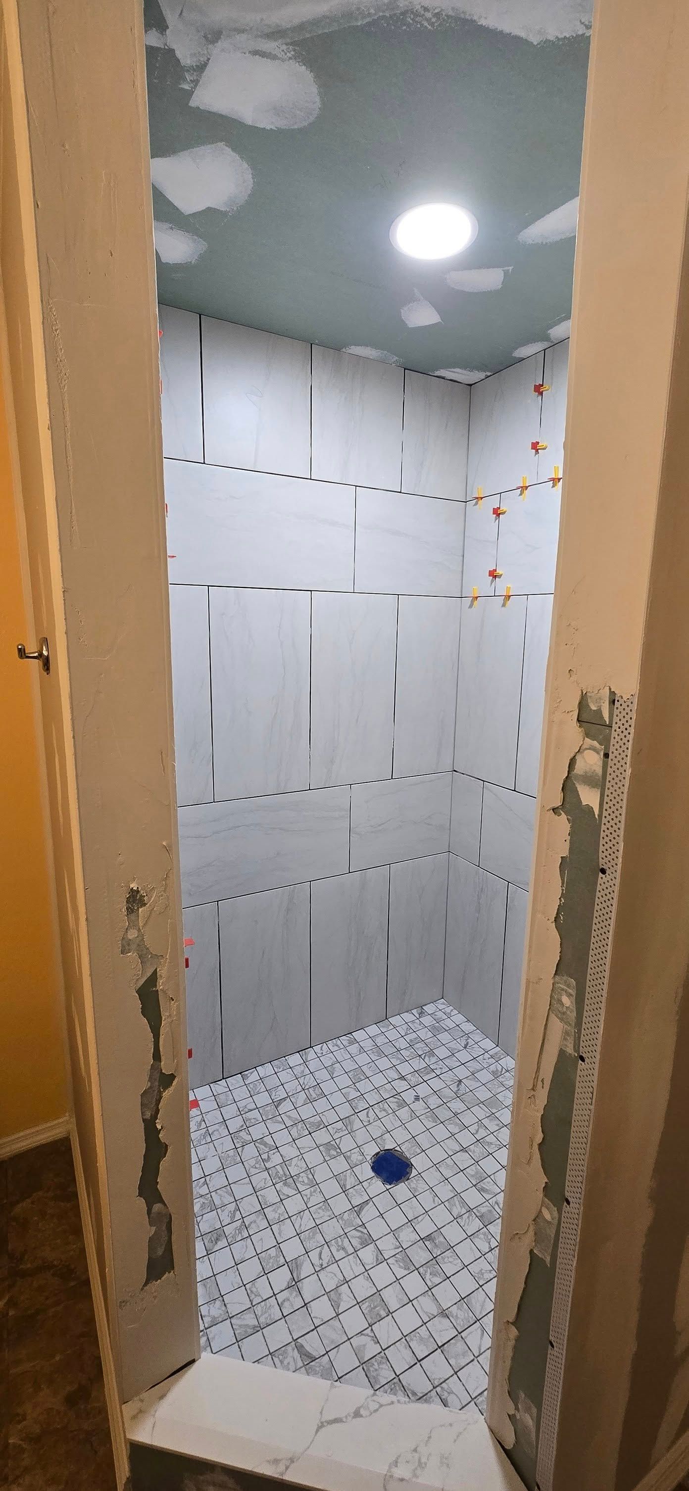 A bathroom with a walk in shower under construction.