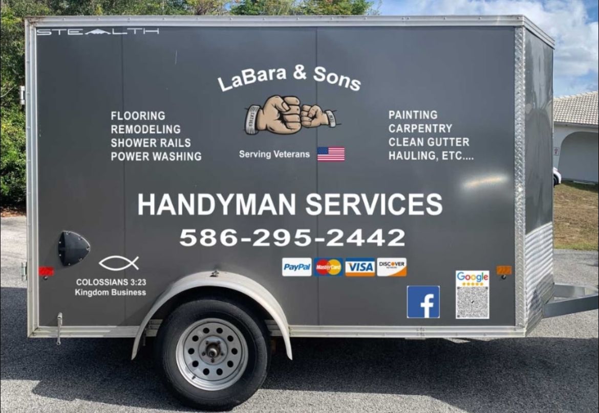 A trailer for handyman services is parked in front of a house