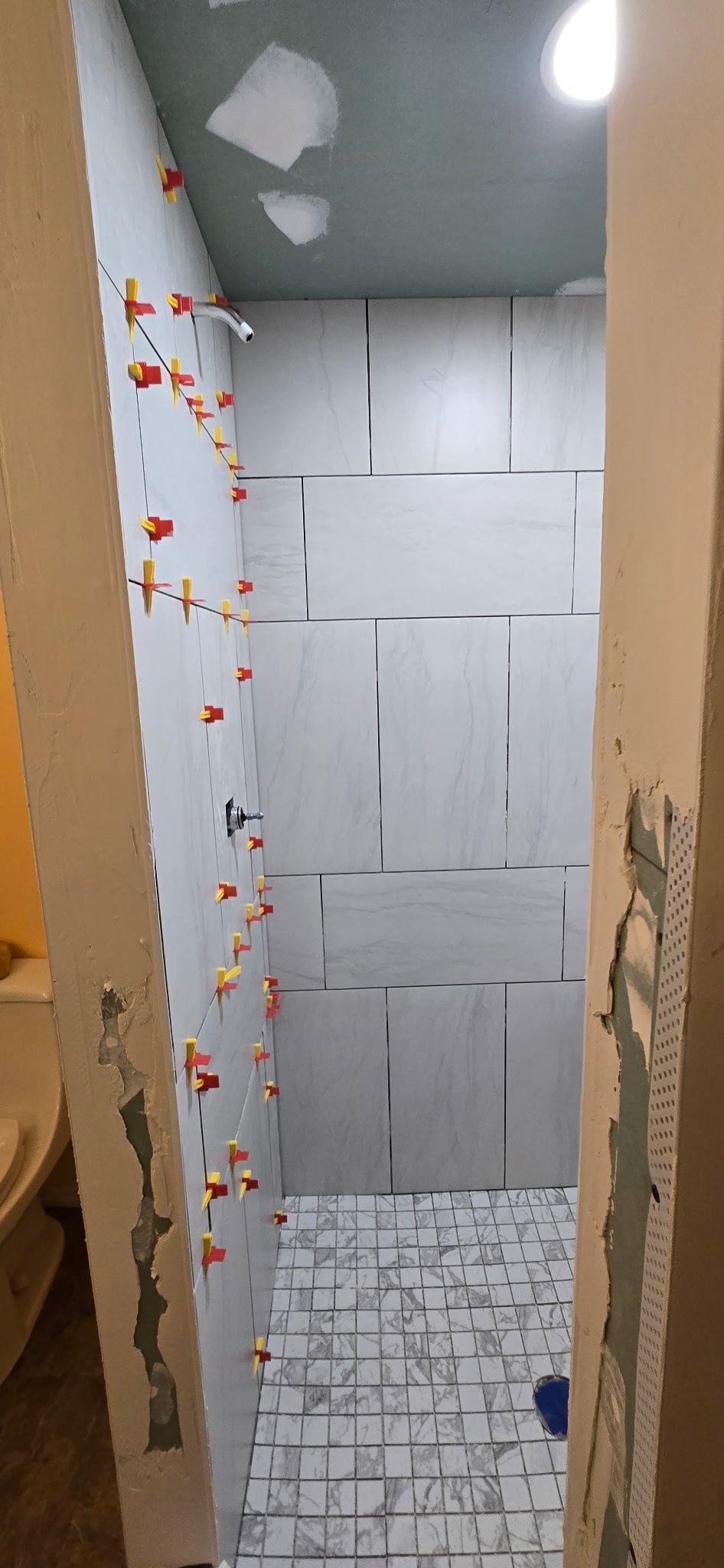 A bathroom with a tiled floor and a shower being built.