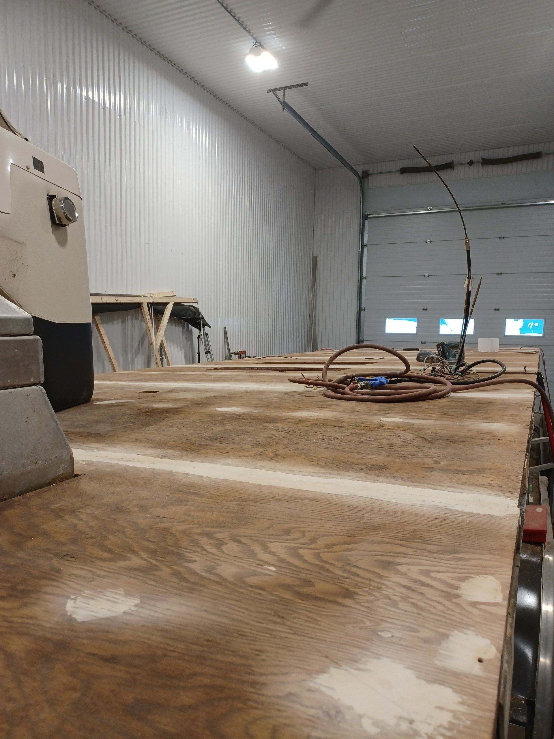 Un plateau de remorque en bois à l'intérieur d'un garage aux murs blancs et à la grande porte.